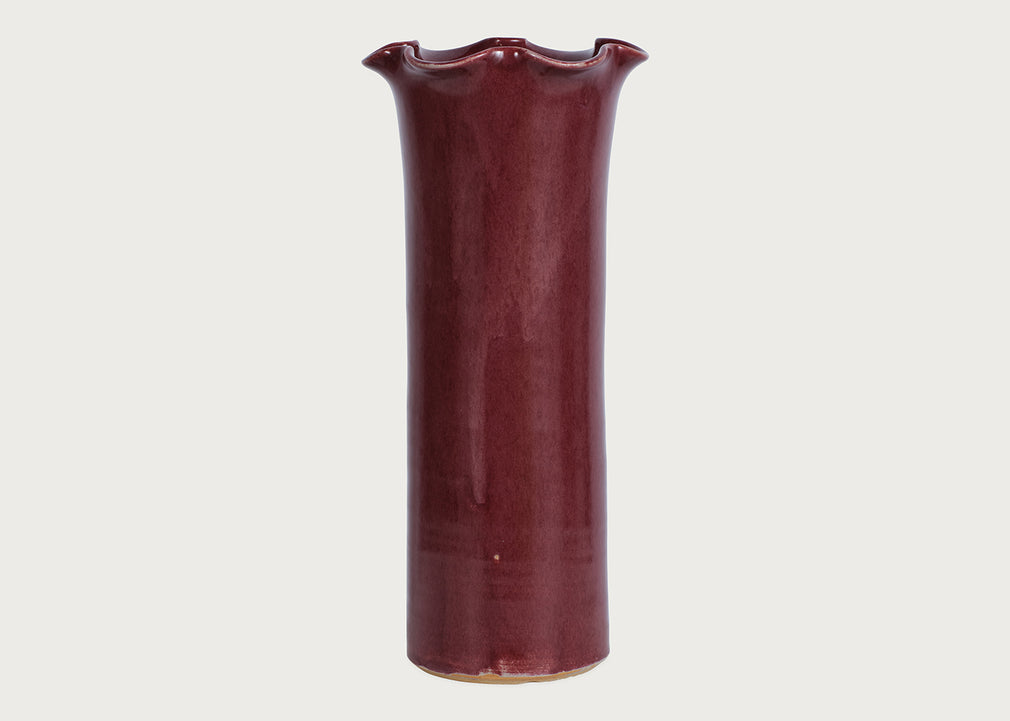 A tall, flared ceramic vase with a glossy deep burgundy glaze, shown against a plain light gray background.