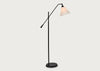 A modern black floor lamp with an adjustable articulated arm and a conical shade, shown illuminated against a plain light gray background.