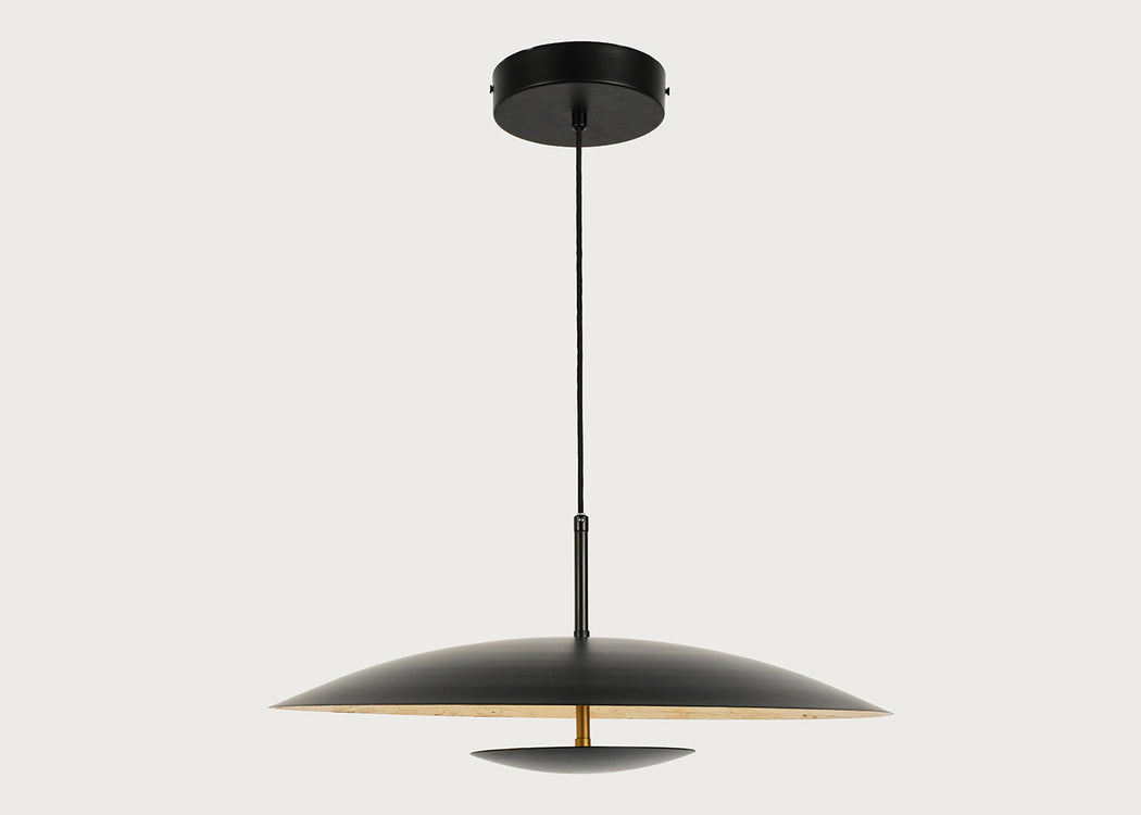 A modern pendant light fixture with a wide, shallow black metal shade, a thin black suspension rod, a circular black ceiling canopy, and a warm brass central support, shown against a solid off-white background.