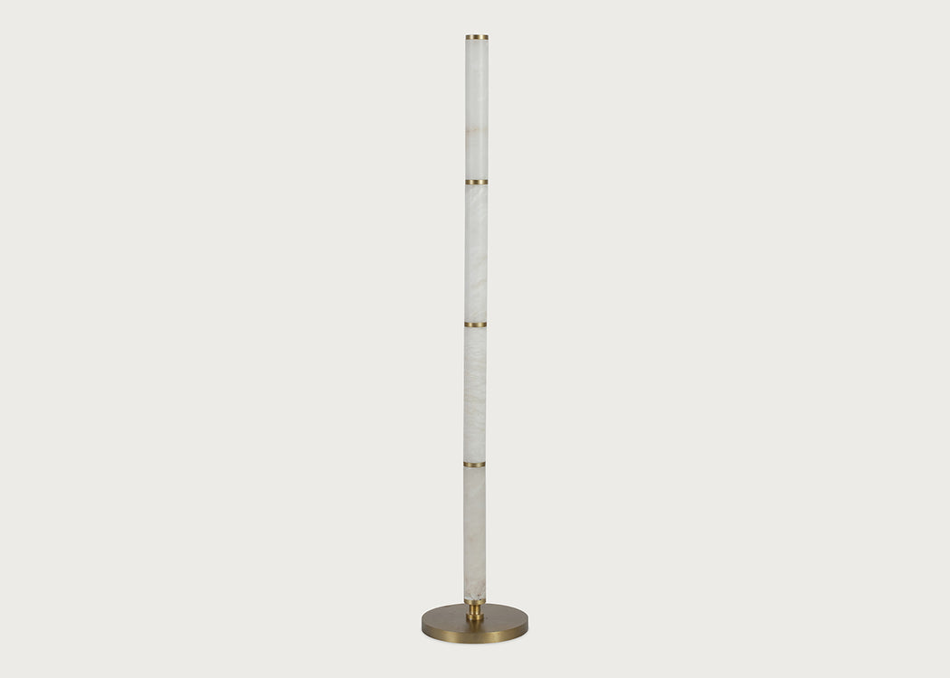 A modern floor lamp featuring a tall, slender alabaster column with gold-toned metal accents and a circular brushed brass base, shown against a solid light gray background.