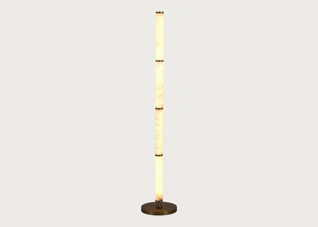 A modern floor lamp with a tall, cylindrical column made of stacked warm-toned alabaster sections, flanked by two slim vertical white panels, and resting on a round dark metal base against a light gray background.