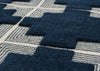 Close-up of a textured area rug with a geometric pattern of dark navy blue blocks and cream-colored wavy lines.