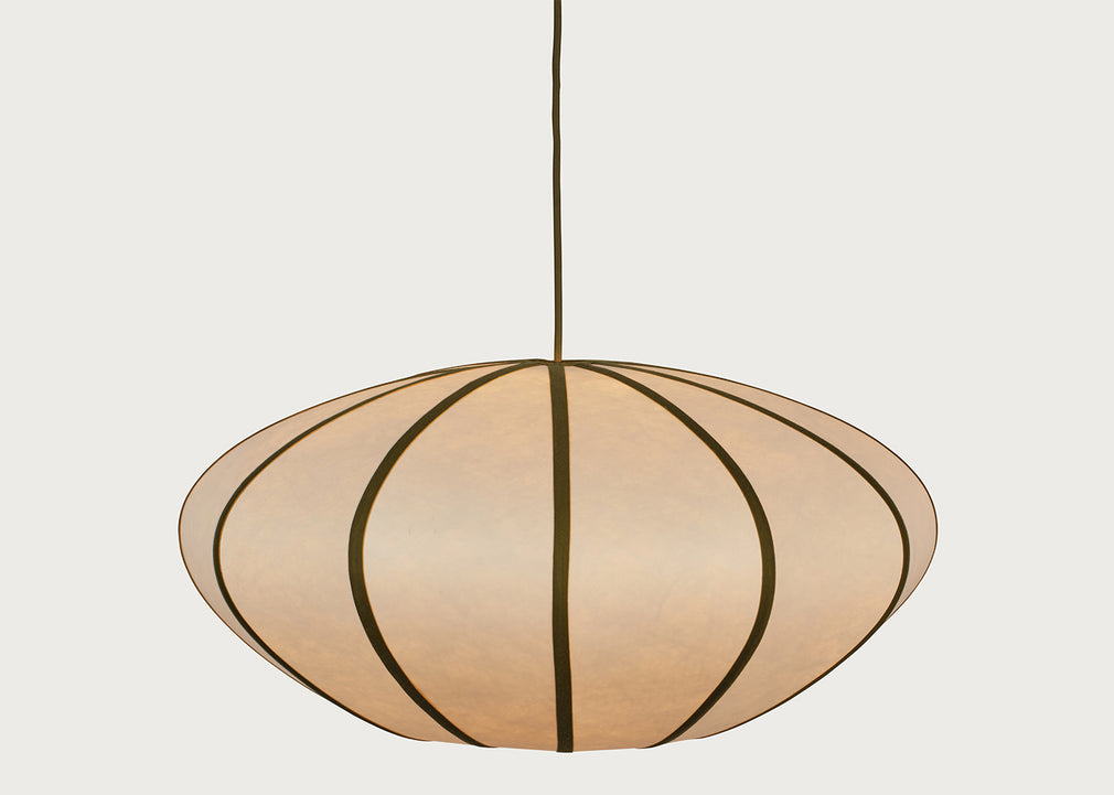 A modern pendant light with a large, rounded, disc-like shade made of warm beige paper or fabric panels divided by dark brown vertical stripes, suspended by a thin dark cord against a light gray background.