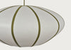 A close-up of a modern pendant light with a white or off-white ribbed shade and olive green vertical bands, suspended by a matching cord against a light gray background.