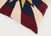 Close-up of a woven throw pillow featuring a geometric design in burgundy, cream, navy blue, and mustard yellow.
