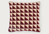 A square throw pillow featuring a geometric pattern of repeating triangles in deep burgundy and cream, set against a plain light gray background.