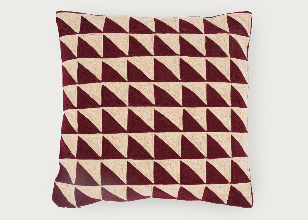 A square throw pillow featuring a geometric pattern of repeating triangles in deep burgundy and cream, set against a plain light gray background.