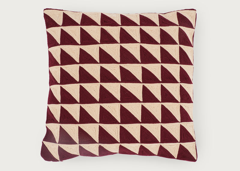 A square throw pillow featuring a geometric pattern of repeating triangles in deep burgundy and cream, set against a plain light gray background.