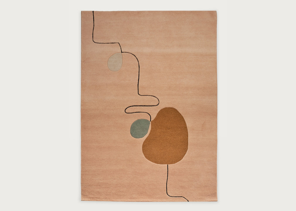 An abstract area rug with a warm peach-beige background, featuring organic shapes in brown, sage green, and light gray, connected by thin black lines, shown flat against a light gray background.